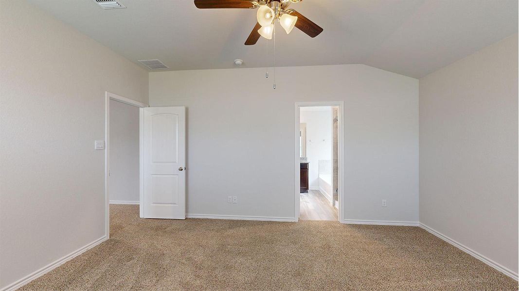 Carpeted room featuring a vaulted ceiling and a wood-finish ceiling fan with integrated lighting Carpeted room featuring a vaulted ceiling and a wood-finish ceiling fan with integrated lighting