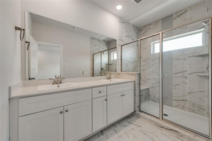 Bathroom featuring dual vanity, tile patterned floors, and a shower with door