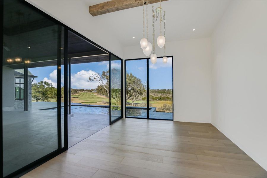 Unfurnished dining area with suspended lighting, light wood-style floors, beam ceiling, and golf course view