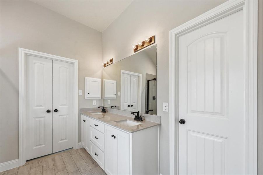 Full bathroom featuring double vanity, light wood-type flooring, a closet, and a stall shower Full bathroom featuring double vanity, light wood-type flooring, a closet, and a stall shower