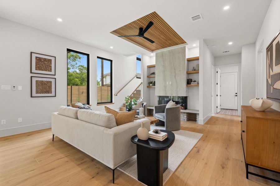 Warm wood floors and a unique wood-slat ceiling insert anchor this light-filled living space.