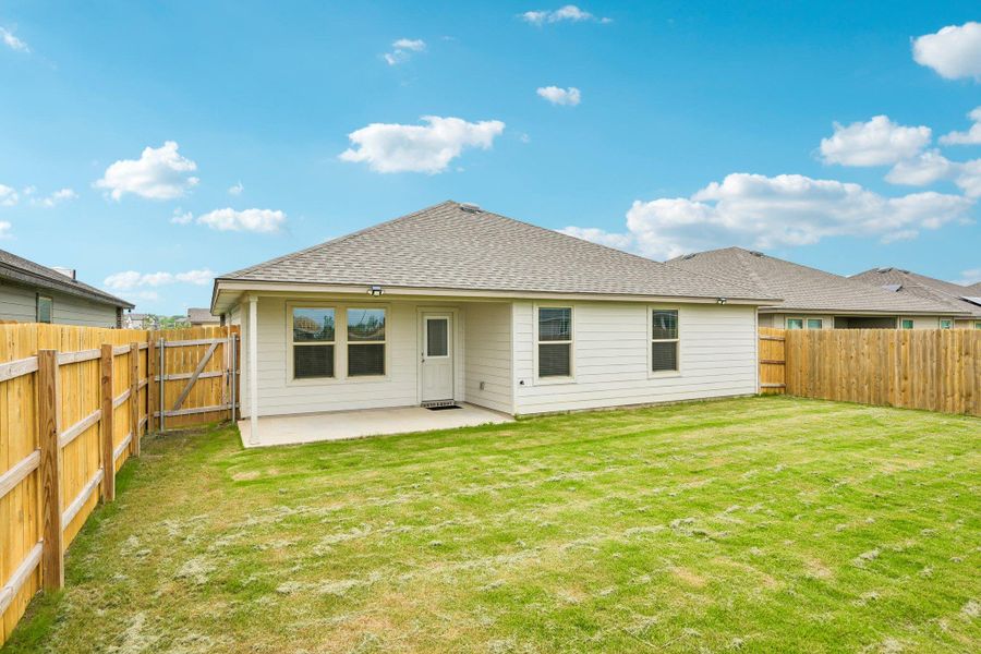 Expansive backyard featuring a manicured lawn, full privacy fencing, and a concrete patio