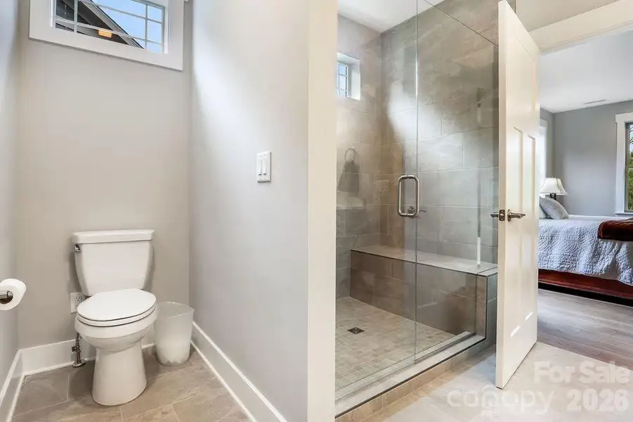 Primary tiled shower with bench seat, window, low profile entry.