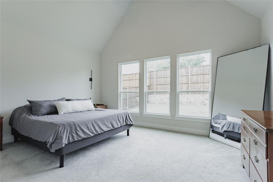 Vaulted ceiling room featuring light gray carpet flooring and three large windows