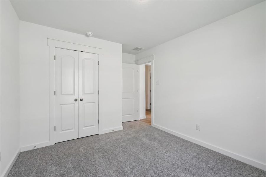 Unfurnished bedroom featuring a closet, baseboards, visible vents, and carpet floors Unfurnished bedroom featuring a closet, baseboards, visible vents, and carpet floors