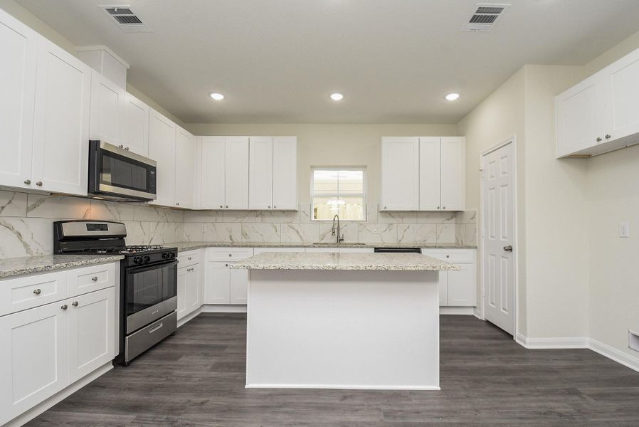 Modern kitchen with white cabinetry, granite countertops, stainless steel appliances, and gray floor. Bright and clean interior space. Modern kitchen with white cabinetry, granite countertops, stainless steel appliances, and gray floor. Bright and clean interior space.