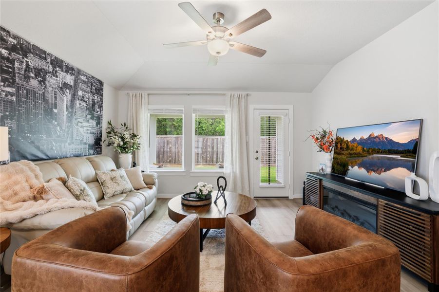 This cozy living room features a modern design with a comfortable leather sofa, two brown armchairs, and a large wall mural. It has ample natural light from large windows and a glass door leading to the backyard. No back Neighbors.