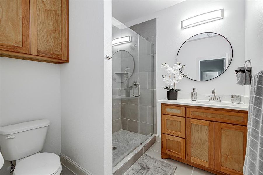 Full bath featuring a stall shower, vanity, and light tile patterned floors