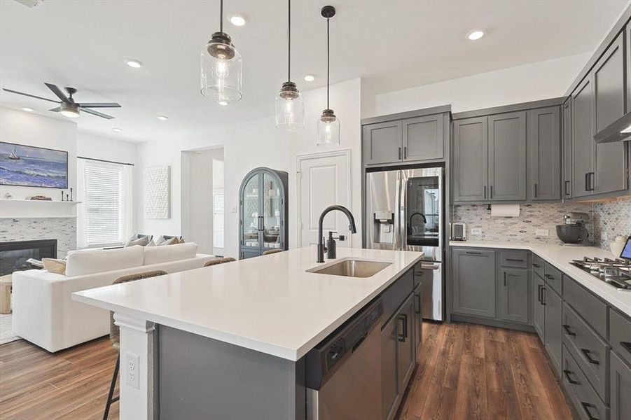 Kitchen featuring a tile fireplace, dark hardwood / wood-style flooring, ceiling fan, and tasteful backsplash