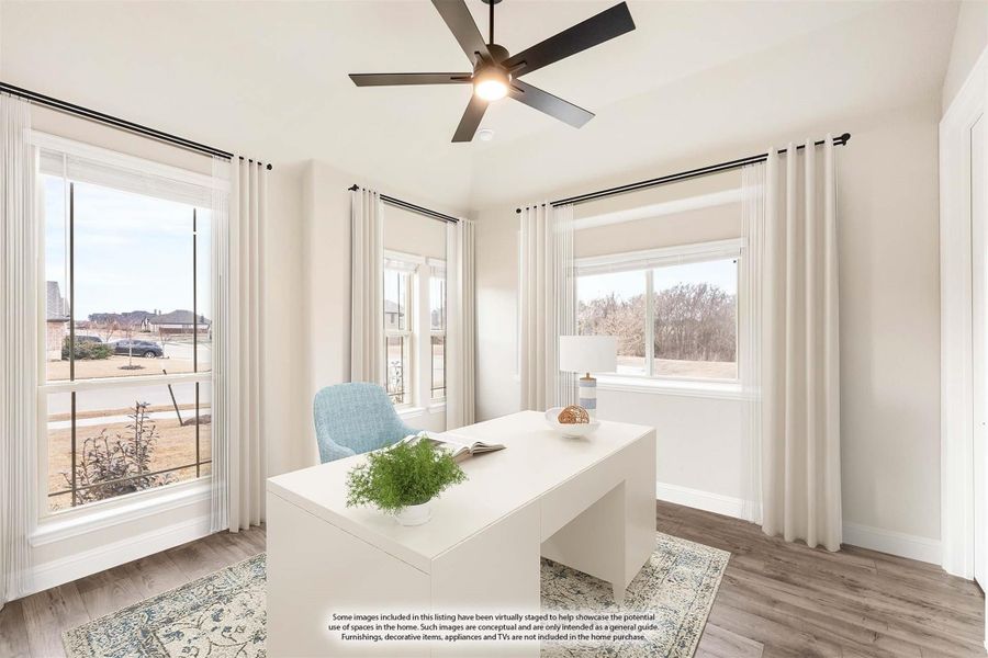 Home office with white desk, ceiling fan, hardwood floors, and three large windows with white curtains Home office with white desk, ceiling fan, hardwood floors, and three large windows with white curtains