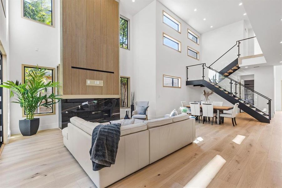 Living room with a towering ceiling and light hardwood / wood-style floors