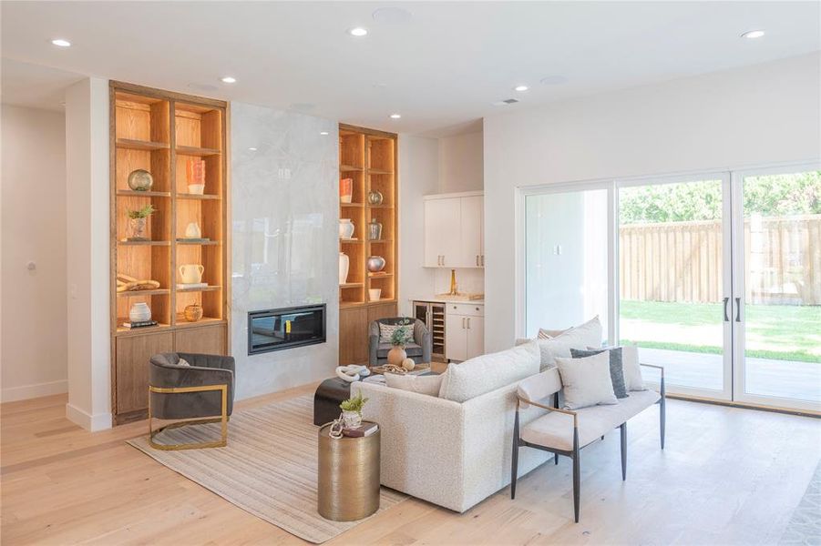 Living room with a large fireplace, light hardwood / wood-style flooring, and beverage cooler