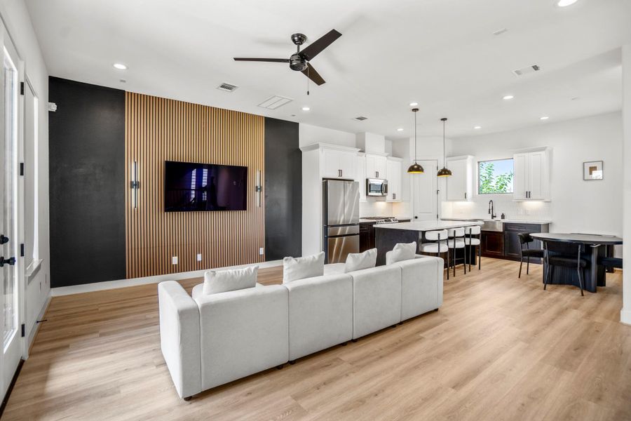 An open-concept living area awaits on the second floor, where natural light pours in through large windows. The focal point is a custom-built entertainment wall—recently crafted with rich wood accents —adding both warmth and a sleek, modern touch to the space.