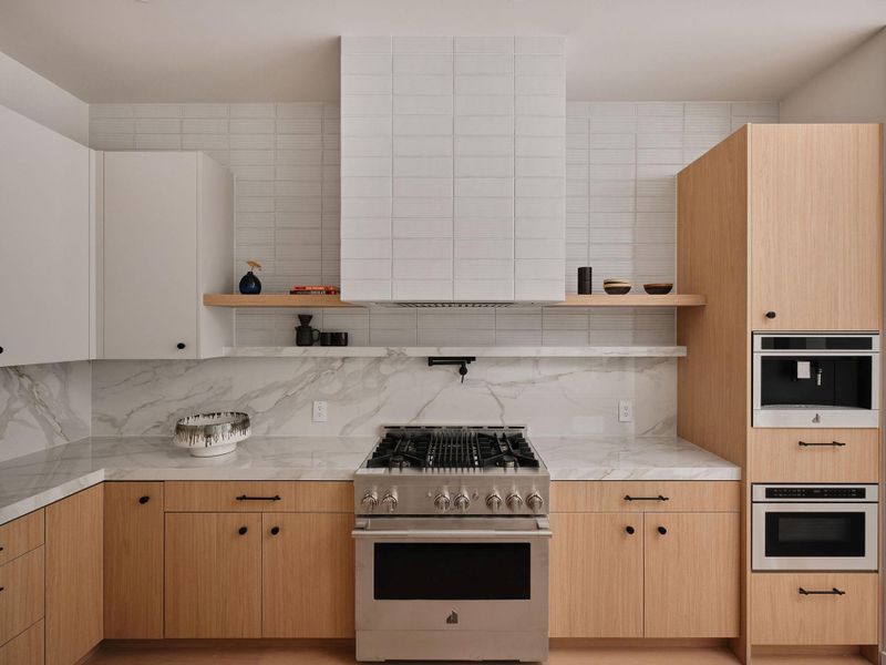 Stainless steel gas range with a tile backsplash and custom range hood