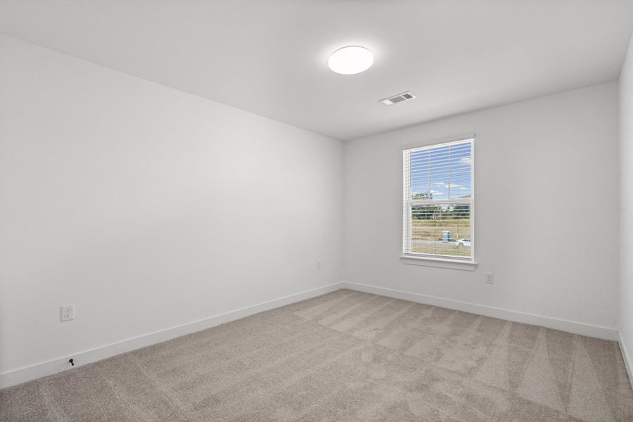 Neutral gray carpet, white walls, and a single window with white blinds