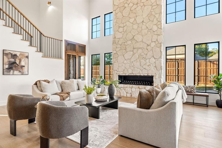 Living room featuring wood finished floors, a stone fireplace, and a towering ceiling Living room featuring wood finished floors, a stone fireplace, and a towering ceiling