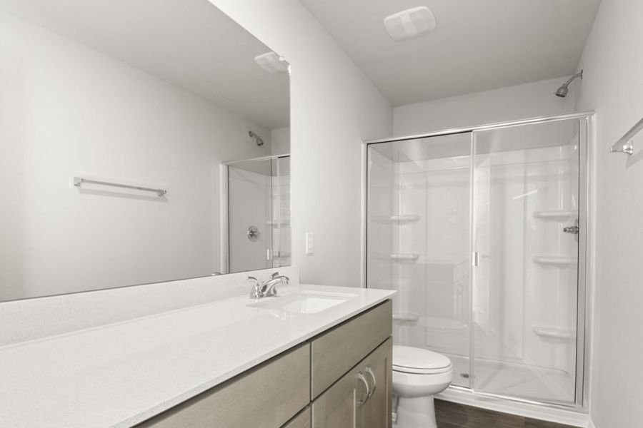 Image of a primary bathroom with a white double vanity, a large mirror and a white vinyl walk-in shower