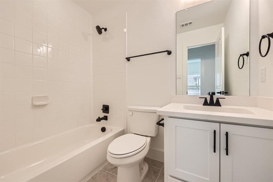 Full bathroom with tile patterned flooring, toilet, vanity, and tiled shower / bath