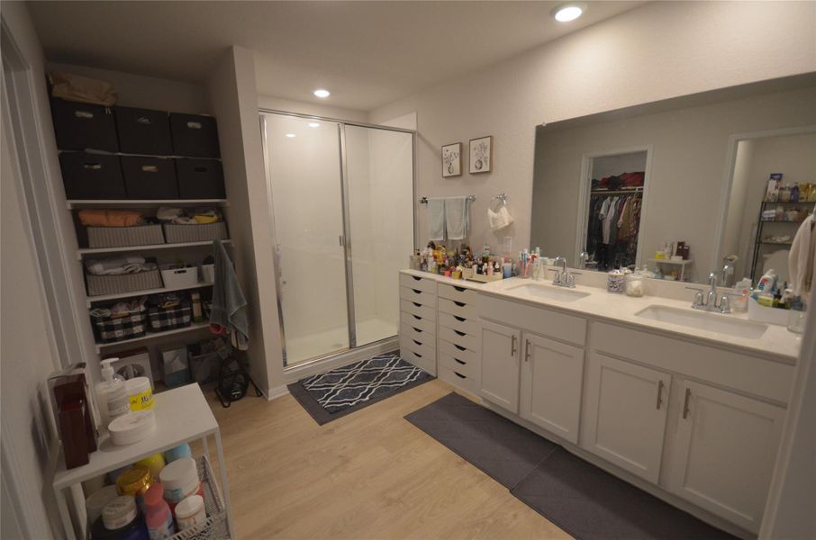 Full bath featuring a shower stall, wood finished floors, a walk in closet, double vanity, and recessed lighting Full bath featuring a shower stall, wood finished floors, a walk in closet, double vanity, and recessed lighting