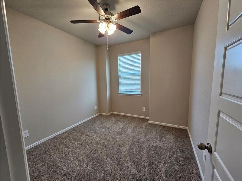 Front bedroom featuring ceiling fan, window coverings and a ceiling fan.
