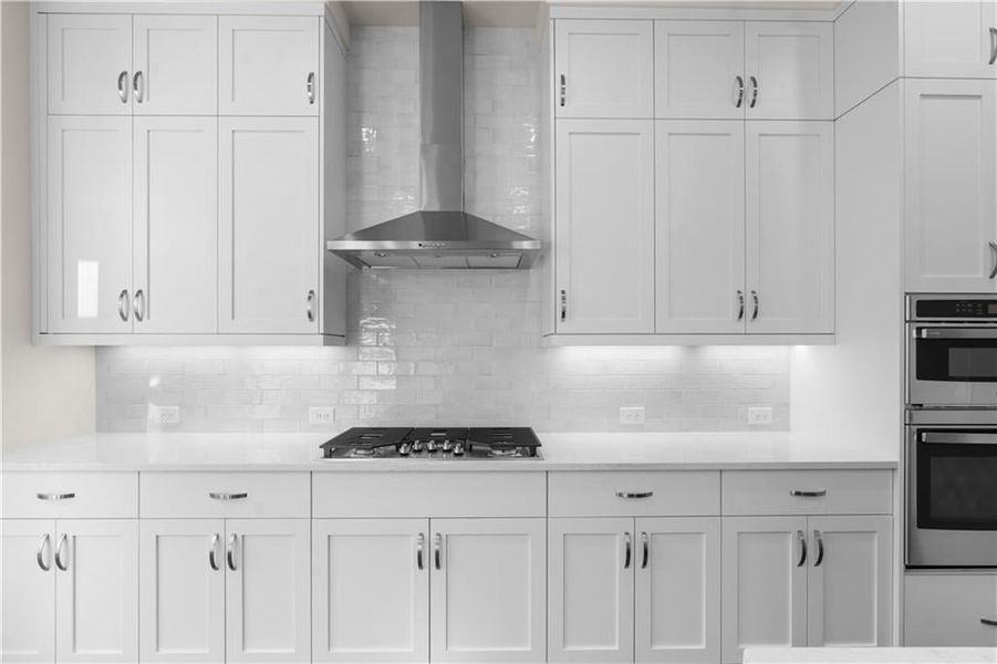 Kitchen with white cabinetry, wall chimney exhaust hood, stainless steel appliances, light stone counters, and backsplash