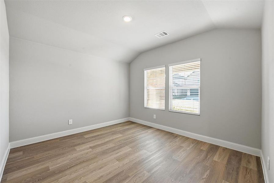 Spare room featuring vaulted ceiling and light wood-style floors