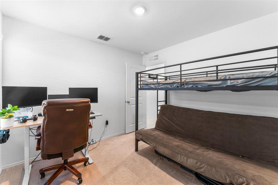 Bedroom featuring light carpet and a desk Bedroom featuring light carpet and a desk