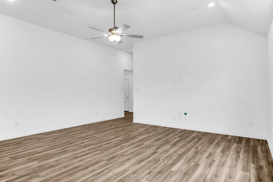 Spacious room featuring wood-finish flooring, vaulted ceiling, and recessed lighting
