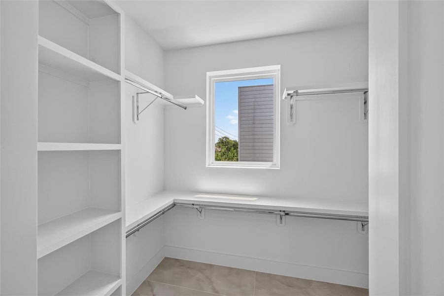 Primary closet with tiled floor, custom shelves and steel rods for durability