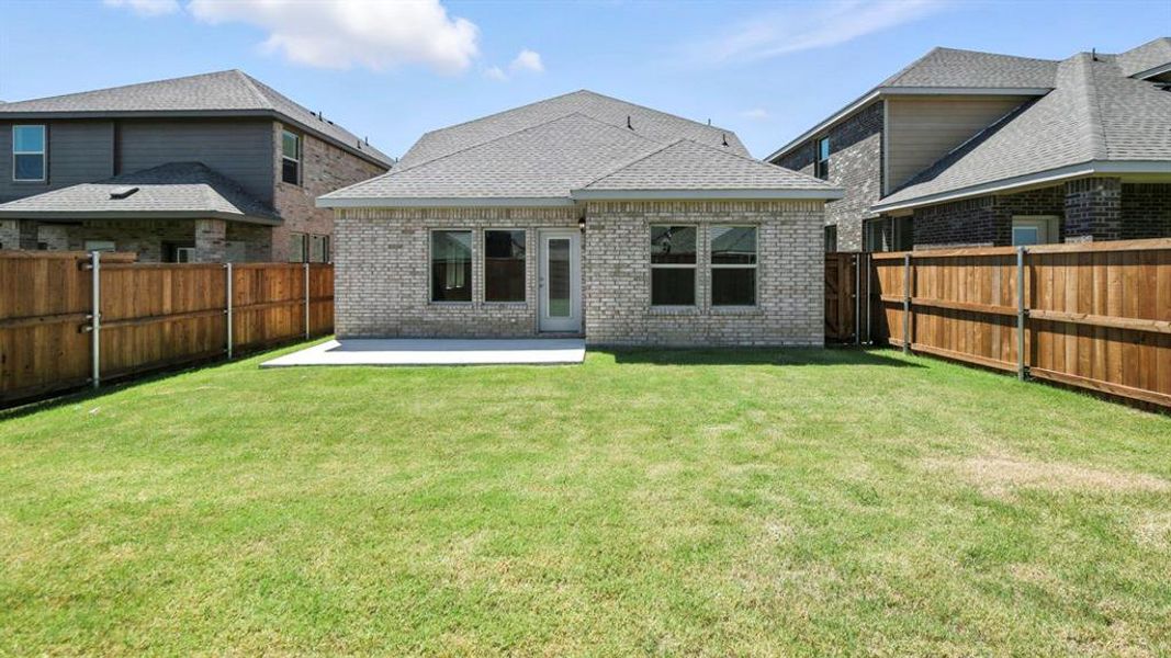 Back of property featuring brick siding, a patio area, a fenced backyard, and a shingled roof