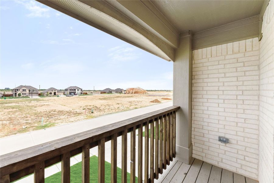 Covered balcony with wood railing and brick wall overlooking a new housing development under construction Covered balcony with wood railing and brick wall overlooking a new housing development under construction