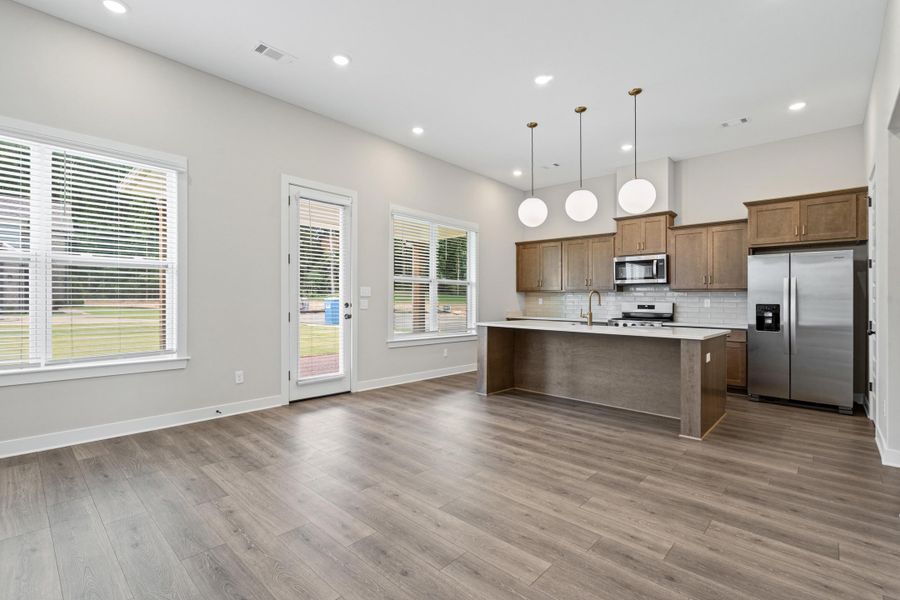 Open-concept living space featuring wood-finish flooring, recessed lighting, and a kitchen island with pendant lighting Open-concept living space featuring wood-finish flooring, recessed lighting, and a kitchen island with pendant lighting