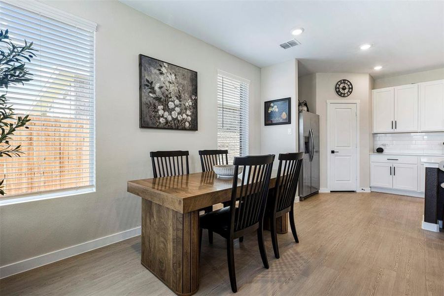 Open-concept dining area featuring wood-finish flooring, recessed lighting, and white horizontal blinds Open-concept dining area featuring wood-finish flooring, recessed lighting, and white horizontal blinds