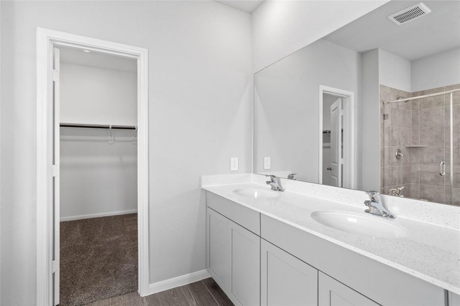 Modern primary bath features dual vanities with sleek cabinetry, a quartz countertop, and chrome fixtures for a truly contemporary feel.