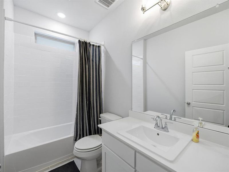 Full bathroom featuring shower / bath combo, vanity, dark tile patterned flooring, and recessed lighting