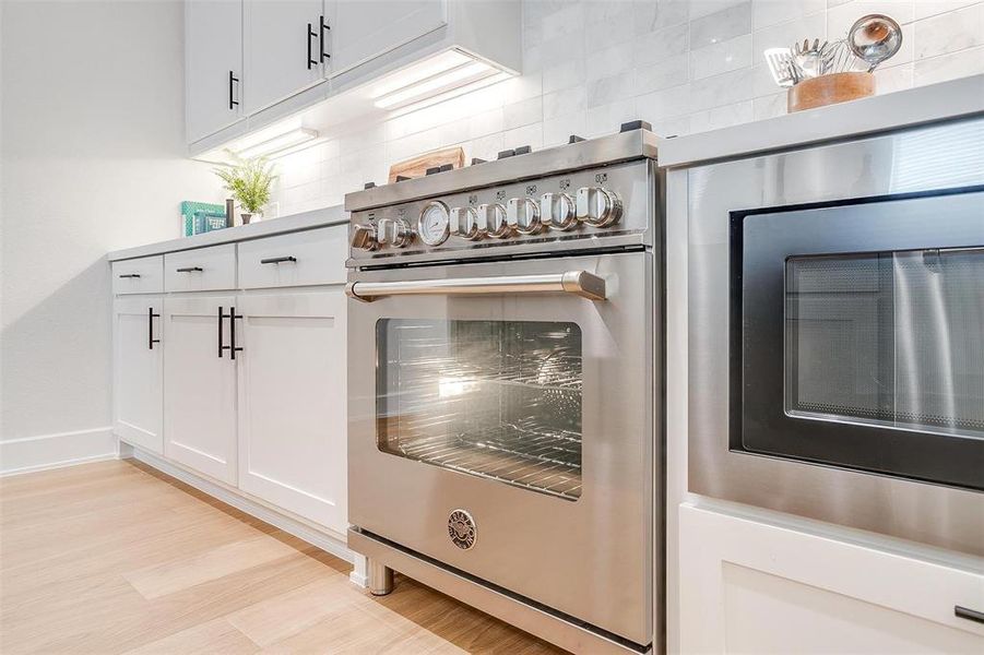 Kitchen with white cabinets, stainless steel stove, and built in microwave Kitchen with white cabinets, stainless steel stove, and built in microwave