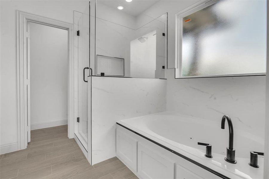 Bathroom with a tub with jets, a stall shower, and wood finished floors Bathroom with a tub with jets, a stall shower, and wood finished floors
