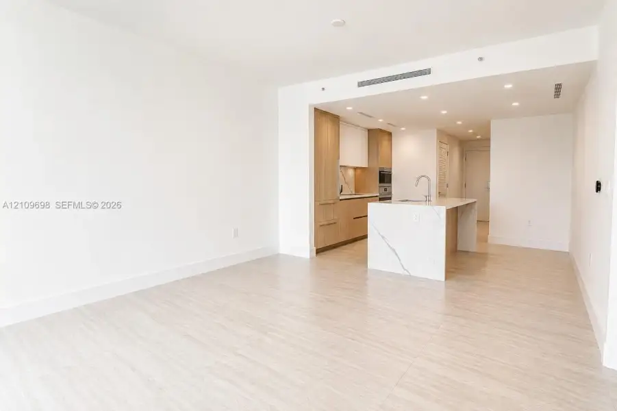 Open-concept space with light-toned wood-finish flooring and recessed ceiling lighting