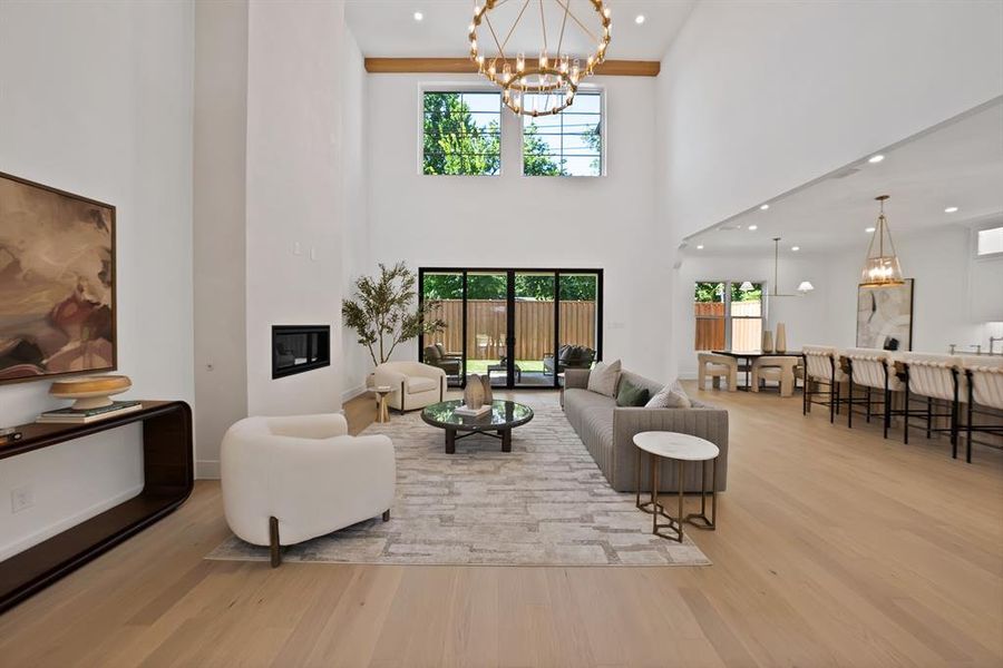 Spacious living area featuring high ceilings, wood-finish flooring, and a modern fireplace