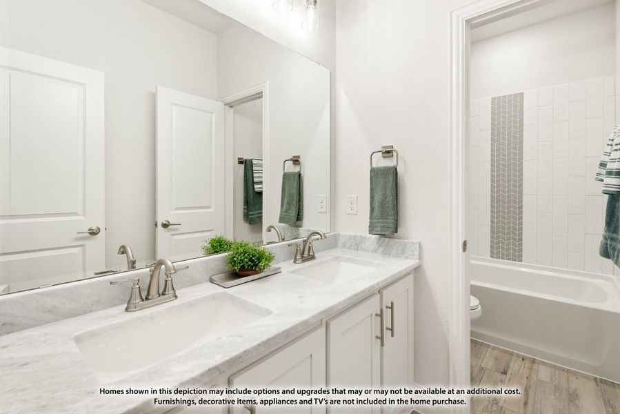 Bathroom with double sink vanity, marble countertops, white cabinets, and tiled bathtub surround Bathroom with double sink vanity, marble countertops, white cabinets, and tiled bathtub surround