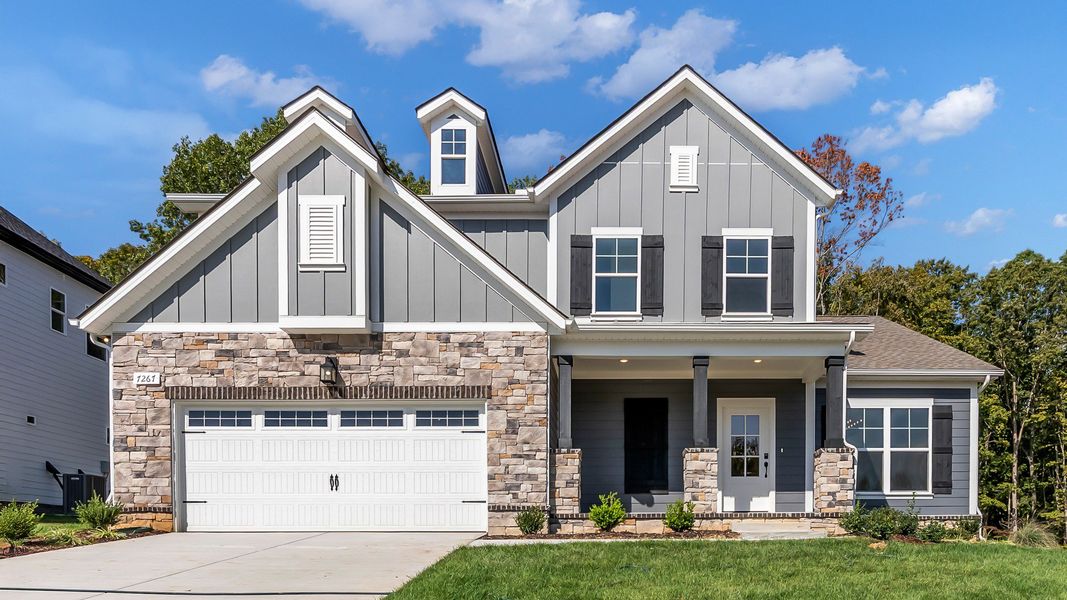 Elegant farmhouse with rustic wood shutters, sleek dark siding, and timeless stone accents in Brush Creek.