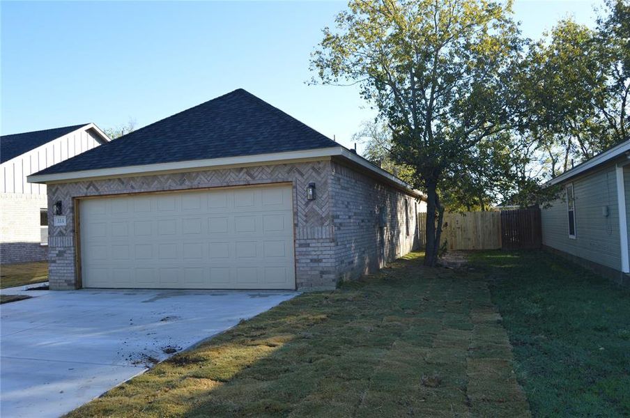 View of side of home featuring a yard and a garage