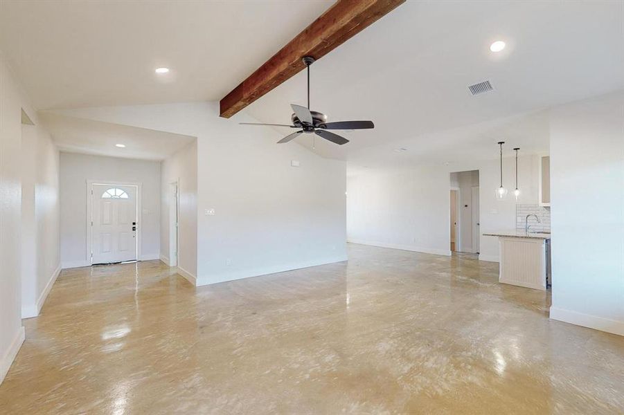 Unfurnished living room with ceiling fan, sink, and lofted ceiling with beams