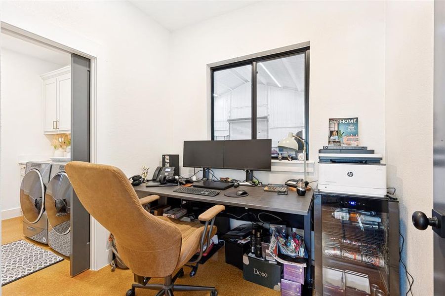Dedicated workspace featuring a large black-framed window, warm-toned flooring, and a sliding pocket door Dedicated workspace featuring a large black-framed window, warm-toned flooring, and a sliding pocket door