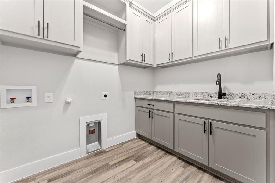 Laundry area with cabinets, sink, washer hookup, hookup for an electric dryer, and light hardwood / wood-style flooring