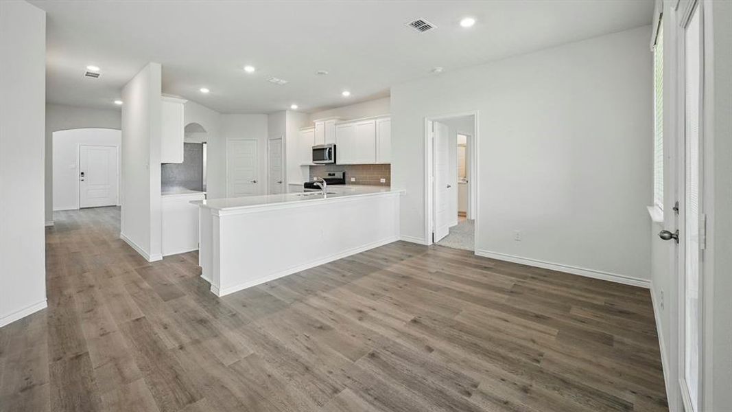 Open-concept living area with wood-finish flooring, recessed lighting, and a white kitchen island