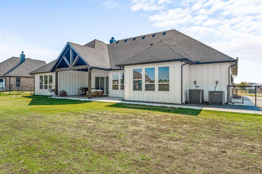 Rear view of house with board and batten siding, a shingled roof, and a patio area
