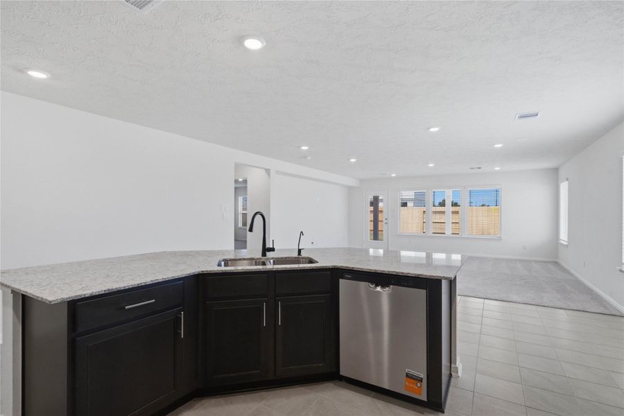 Featured here is the gorgeous granite countertops and the view looking out to the open concept living spaces and backyard views!