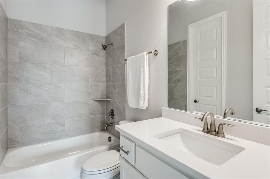 Full bathroom featuring toilet, tiled shower / bath combo, and vanity