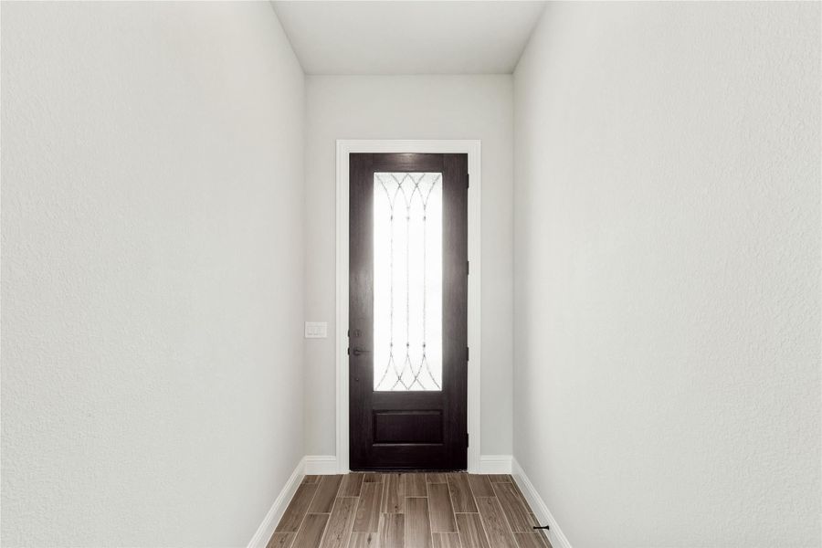 Entryway with dark wood front door featuring decorative glass panel and wood-look tile flooring Entryway with dark wood front door featuring decorative glass panel and wood-look tile flooring